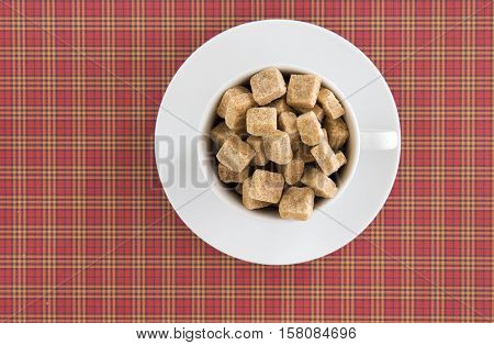 Raw cane brown sugar cubes in white cup. Diet unhealty sweet addiction concept