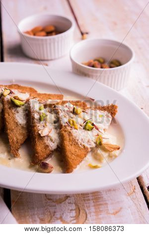Shahi tukda prepared - deep fried bread in ghee, garnish with sweetened cream and dry fruits.