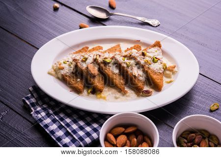 Shahi tukda prepared - deep fried bread in ghee, garnish with sweetened cream and dry fruits.