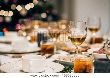 Dining table full of a variety of delicious festive food with a Christmas tree in the background