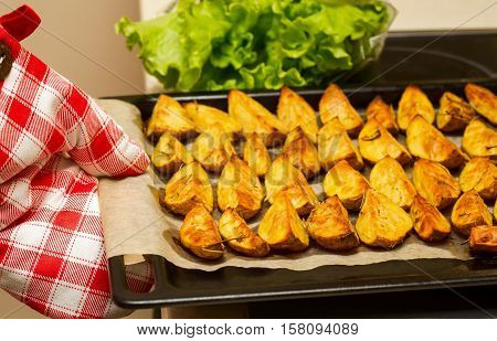 Kitchen protective glove with ovenbaked potatoes with garlic and herbs