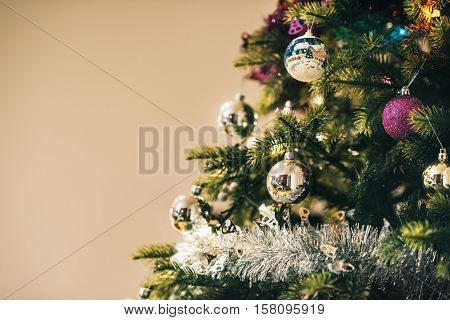 Closeup of tinsel and decorations hanging from the branches of a Christmas tree in a home during the festive season