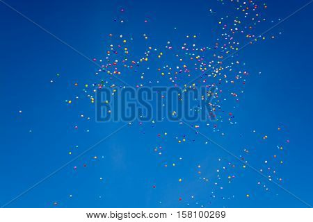 Hundreds of colorful ballons are flying through the blue cloudless sky