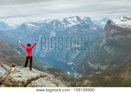 Tourism vacation and travel. Happy free tourist woman with arms raised outstretched up looking at Geirangerfjord and mountains landscape from Dalsnibba viewpoint Norway Scandinavia.