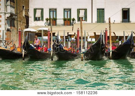Venice Italy - September 8 2016: Gondolier making agreement about making a deal with touristic group. A row of gondolas waiting for clients in Venice Italy