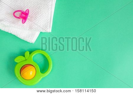 children's clothes and baby booties on green background top view
