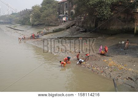 KOLKATA, INDIA - FEBRUARY 10: People bathing in river Hooghly under the busy Howrah bridge in Kolkata on February 10, 2016.
