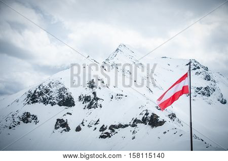 Scenic picture-postcard view of famous place, Grossglockner mountain and Austia flag with cloud & fog, Austria