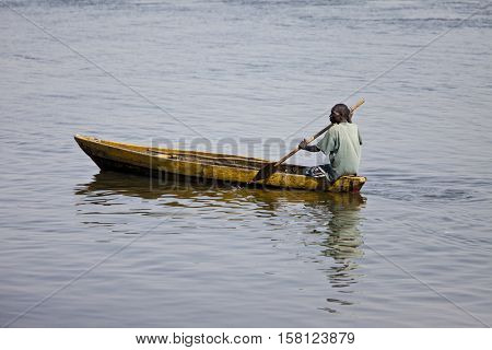 JUBA, SOUTH SUDAN-FEBRUARY 19 2013: unidentified man paddles traditionally made canoe on the White Nile through Juba, capital of South Sudan
