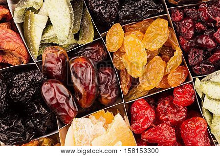 Assortment of dried fruits closeup background in square cells. Decorative pattern of dry exotic fruit. Top view.