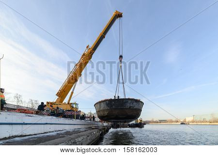 MOSCOW, RUSSIA - NOVEMBER 11, 2016: State Unitary Enterprise Mosvodostok performs recovery vessels on coastal winter parking. Car crane lifts the barge from Moscow river.