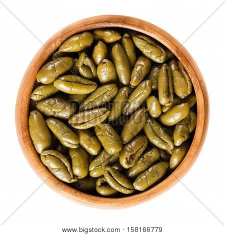 Dried green olive halves in a wooden bowl. Half table olives, dried ripe fruits of Olea europaea. Isolated macro food photo close up from above on white background.