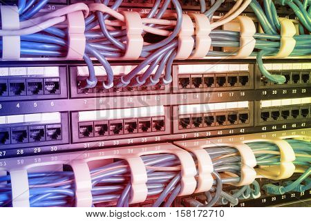 Server rack with blue internet patch cord cables connected to patch panel in server room. Gradient