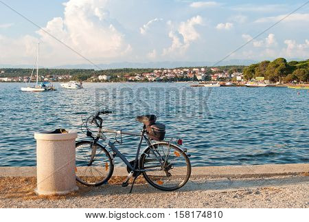 A bicycle standing near the sea against the background of the Croatian town Zadar and several motor boats sailing in the water