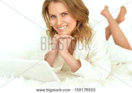 Beautiful young woman with laptop on her bed at home