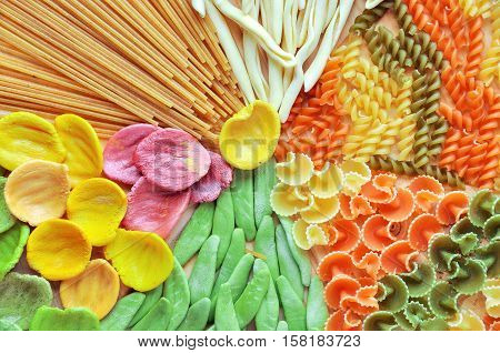 Assortment of colorful pasta close up dyed with natural dye from carrots potatoes spinach and beetroot. Multicolored pasta with a different shape.