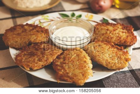 Traditional ukrainian food - deruny. Fried potato pancakes with sour cream on the check tablecloth