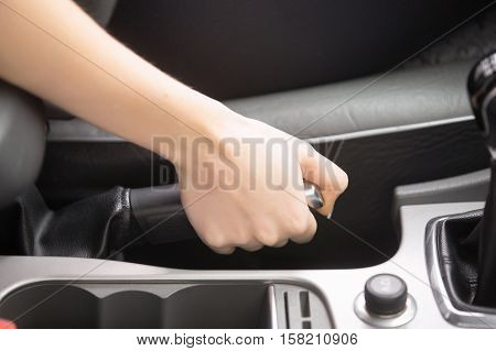 Close up of female hands holding a handbrake lever to keep the vehicle stationary