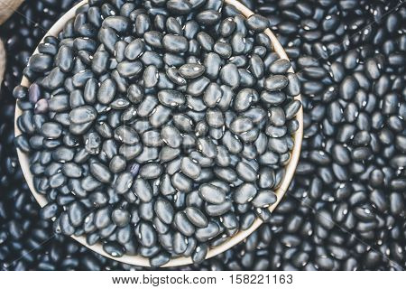 Close-Up View Of Black Beans Scattered Beans Around On A Cup With Beans Background. (View From Above)
