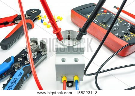 Measurement of voltage in electrical outlet with a multimeter on a white background