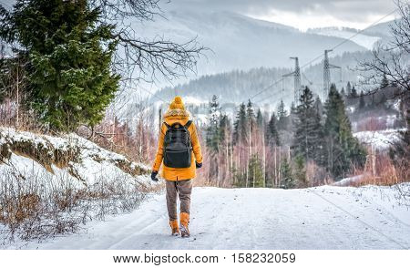 woman traveler walking along the winter road in the woods