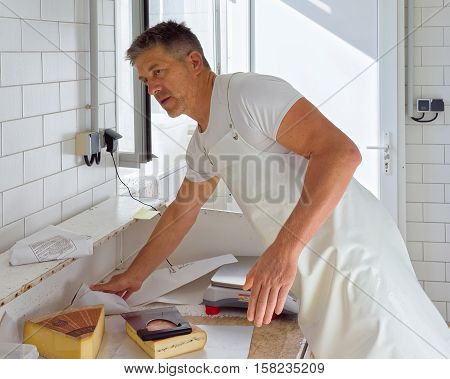 Cheese Maker Cutting Morbier Cheese At Dairy