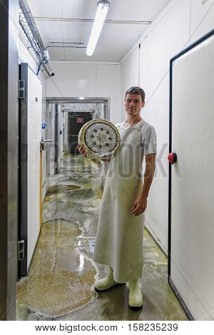 Cheese Maker Holding Wheel Of Cheese In Franche Comte Dairy
