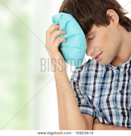 Man met ijs zak voor hoofdpijn, migraine, kater en letsel