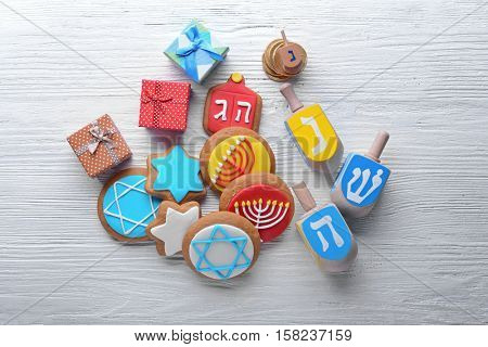Composition of tasty cookies and dreidels for Hanukkah on light wooden table