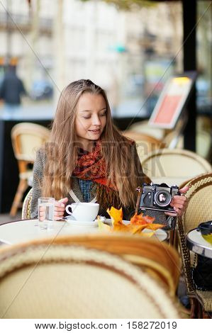 Beautiful Young Woman In A Cafe Holding An Old-fashioned Photo Camera