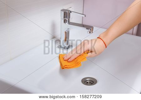 Female Hands Cleaning Tap With Orange Cloth. Spring Clean Up