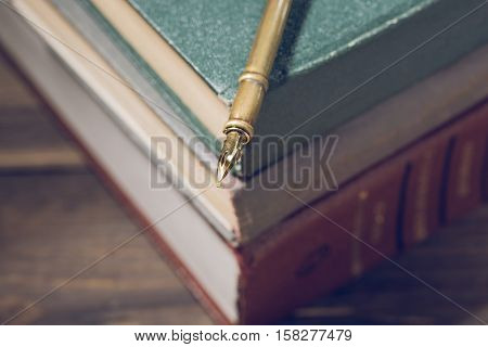 Closeup of fountain pen on stack of old books.