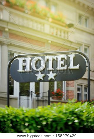 Detail of a luxury Two stars hotel with beautiful building in the background on a beautiful sunny day. Tilt shift lens used to accent the word "hotel" and to emphasize the background
