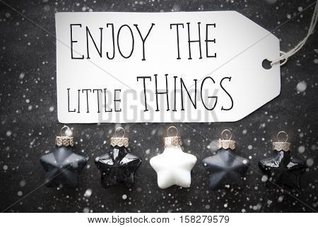Label With English Quote Enjoy The Little Things Black And White Christmas Tree Balls On Black Paper Background With Snowflakes. Christmas Decoration Or Texture. Flat Lay View