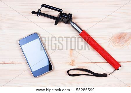 Monopod and phone on wood desk. Gadgetry on board,