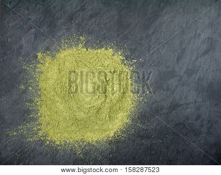 Indigo indigofera tinctoria powder pile on the dark slate