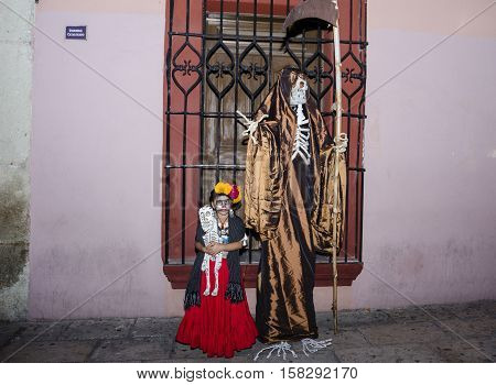 OAXACA, OAXACA, MEXICO - NOVEMBER 1, 2016: Little girl dressed up like Frida Kahlo poses with the Death at day of the dead celebration in Oaxaca, Oaxaca, Mexico