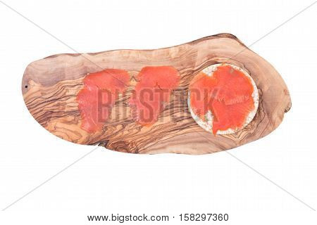 Smoked wild pacific sockeye salmon on organic brown rice cake and olive wood cutting board isolated on white background