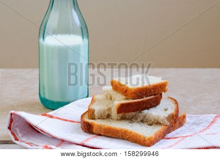 White rye loafs of bread and green bottle of milk. Plain rural breakfast. Selective focus.