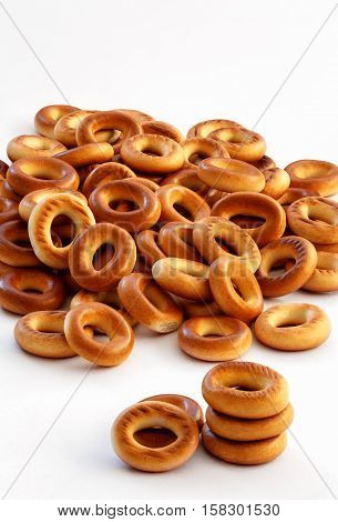 stack pile of bright yellow orange crispy pretzels cookies cracknels Russian or Ukrainian donuts (bubliks) on white background