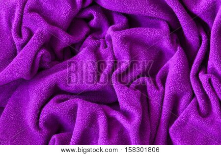 Closeup macro texture of pink violet purple fleece fabric clothing background with wrinkles and folds
