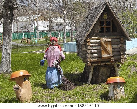 A fairy house of unmarried old witch with a wooden leg in the summer garden on a green lawn.