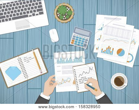 Man analyzes documents. Accounting, analytics, market analysis, report, research, planning concept. Hands on the desktop hold documents. Charts, diagrams, graphs on the paper. Office space top view.
