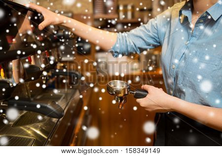 equipment, people and technology concept - close up of woman making coffee by machine at cafe bar or restaurant kitchen over snow
