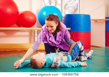 Cute Kid With Disability Has Musculoskeletal Therapy By Doing Exercises In Body Fixing Belts