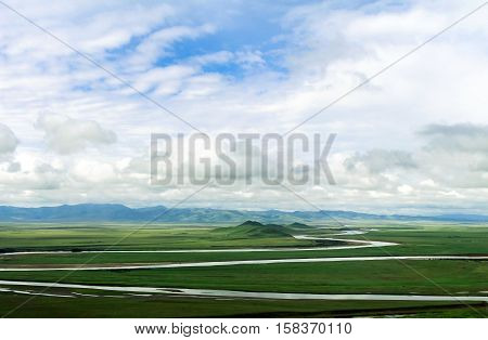 landscape of green grassland and curly rivers