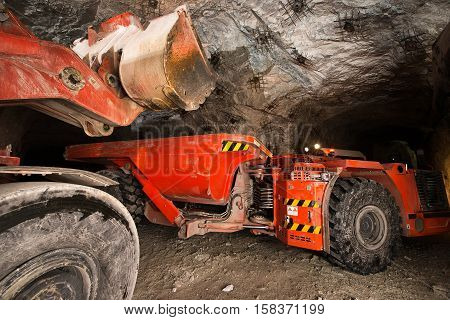 Gold mining underground. Loading truck with golden ore in the tunnel.