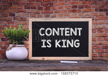 CONTENT IS KING word on blackboard with green plant