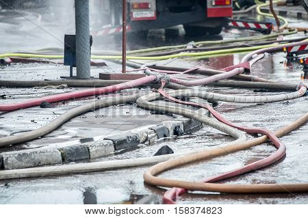 fire hoses on the sidewalk of asvalte in water flows after extinguishing