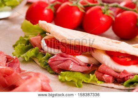 Piadina with ham and lettuce on wooden table.